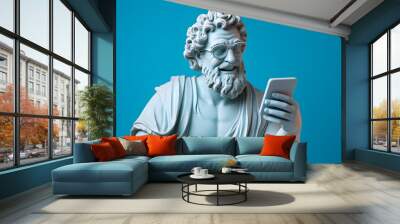 Ancient Greek God statue with curly hair, smiling, reading text message on modern smartphone, on pastel blue background Wall mural