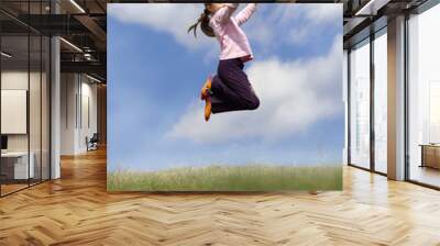 Girl jumping on the meadow, with blue sky and clouds in backgrou Wall mural