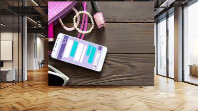 Things from open woman purse on wooden background . Lady's accessories and cosmetics fell out of the pink handbag. Phone chat UI for the template. Wall mural