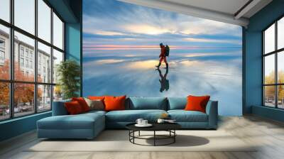 man traveler with backpack walking on the salt lake at sunset. sky with clouds are reflected in the  Wall mural