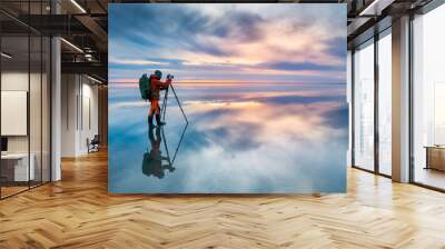 Photographer traveler taking photo of the salt lake at sunset. Blue sky with clouds are reflected in the mirror water surface. Professional photographer using tripod and dslr camera Wall mural