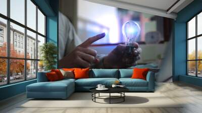 businessman hand holding creative light bulb with power line technology, analysis solution and devel Wall mural