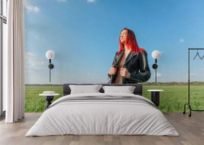 Girl in a leather jacket in nature. sky background Wall mural