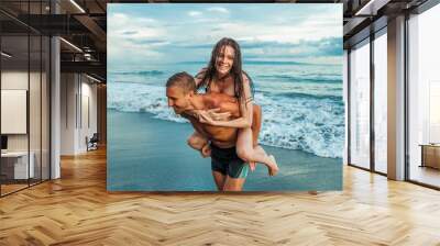 girl on the back of a man on his back to the beach Wall mural