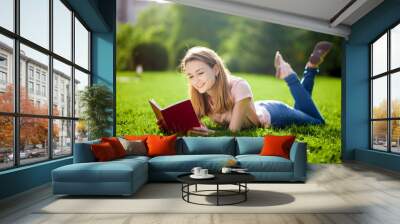 Girl reading book lying on the lawn Wall mural