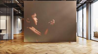 Portrait of praying boy on dark background Wall mural