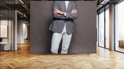 Tall handsome man dressed in white turtleneck, white jeans and grey jacket posing on the grey background Wall mural