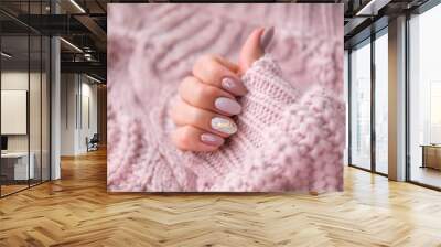 Women's hands with a beautiful  oval manicure in a warm pink knitted sweater. Winter trend, polish beige nails with gel polish, shellac. Copy space. Wall mural