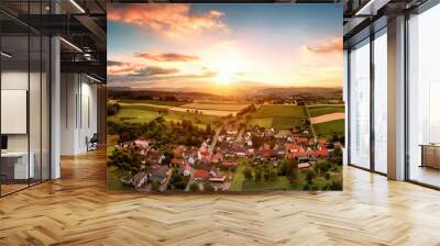 Aerial panorama of a village surrounded by fields at sunrise, with beautiful colorful sky and warm light Wall mural