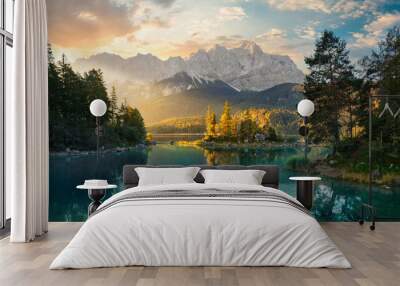 Painterly lake scenery in Germany with mountains reflected in the teal water and a beautiful ray of morning sunlight illuminating some trees  Wall mural