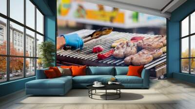 Cook turns over the grilled sausage and vegetables. Street food. BBQ picnic Wall mural