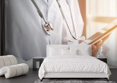 Healthcare medical concept : Doctor standing using tablet computer with white gown suite and wearing Stethoscope on neck for seaching information treating patients in hospital or clinic Wall mural