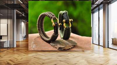 A braided paracord bracelet in khaki and brown on the hand with a brass lock on a flat stone in the standing position Wall mural