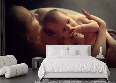 Cute baby girl in her mother's hand hugging her. Image with selective focus and toning Wall mural