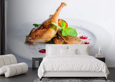 Juicy delicious cooked duck legs served with herbs and sauce in a white plate over white background. Autumn menu in an Italian restaurant Wall mural