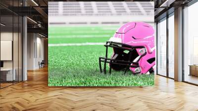 Pink football helmet on green grass field at empty stadium Wall mural