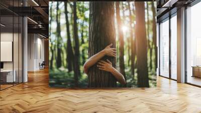 hands embracing a large tree trunk in a dense forest, symbolizing a connection with nature and environmental care.Ecological awareness: social responsibility to preserve nature for future generations. Wall mural