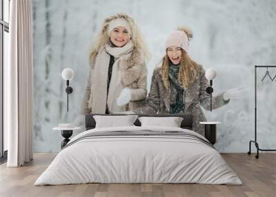 Photo of two blondes throwing snow on walk in winter forest Wall mural