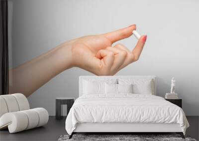 Tablet in a capsule in a woman's hand on gray background. Wall mural