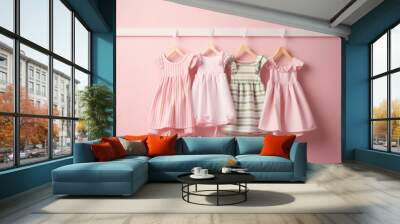 Girl Dresses clothes in pastel colors on white line hanger in a row. Background of a pink colored wall.  Creative concept for a children's clothing store, children's fashion banner. Generative AI Wall mural