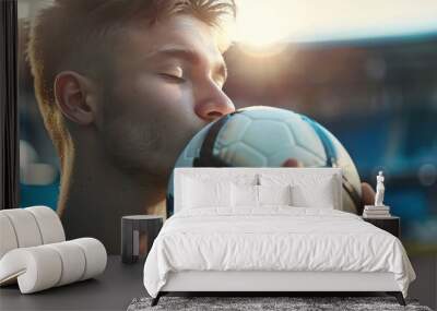 Portrait of a happy young male soccer player kissing a soccer ball. Wall mural