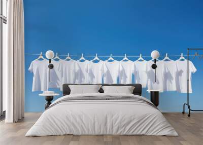 White t-shirts hanging on the line with pegs on clear blue sky background. Many simple white shirts. Wall mural