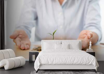 Hands of businessman putting coin into plant sprouting growing up to profit, demonstrating financial growth through saving plans and investment schemes. Wall mural