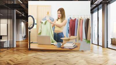 Online selling concept, Fashion designer showing clothes for sales in live streaming at home office Wall mural