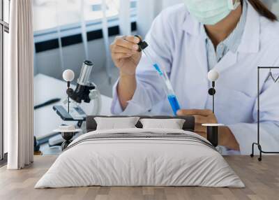 scientists researching in laboratory in white lab coat, gloves analysing, looking at test tubes sample, biotechnology concept Wall mural