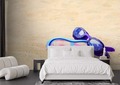 Two pairs of glasses for swimming on a sand background Wall mural