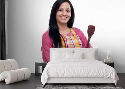 young indian woman holding kitchen utensil against white Wall mural