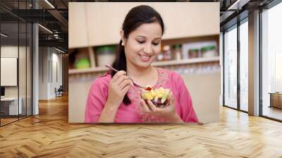 young woman eating fruit salad Wall mural