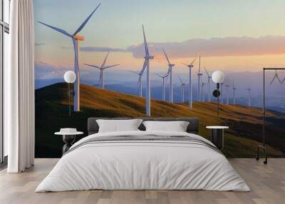 A row of wind turbines stand tall on a grassy hilltop against a colorful sunset sky. Wall mural