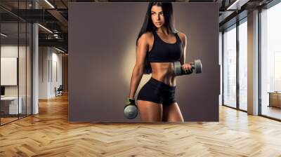 Beautiful fitness woman lifting dumbbells . Fitness sporty woman showing her well trained body . A beautiful girl's body with rippling muscles from strength training . 
 Wall mural