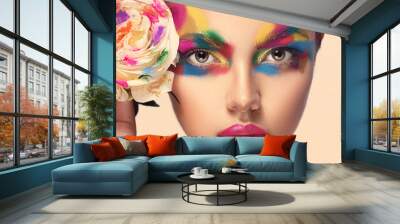 Beautiful girl model with multi-colored paints on her face. Woman with rose flower and bright color make-up. Cosmetics, beauty and makeup.  Spring and summer flowering  shopping Wall mural