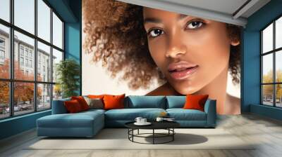 Beauty portrait of african american girl with clean healthy skin on beige background. Smiling dreamy beautiful black woman.Curly hair in afro style Wall mural