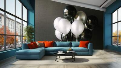 Black and white balloons on a dark black background. Celebration concept / White and black balloons on a dark black background for a holiday, birthday or other holiday. Photo for posters or postcards. Wall mural