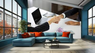 Close up of business partners handshake deal come to agreement. Businesswoman offering batch of hundred dollar bills and euros to male ceo in modern office. Wall mural