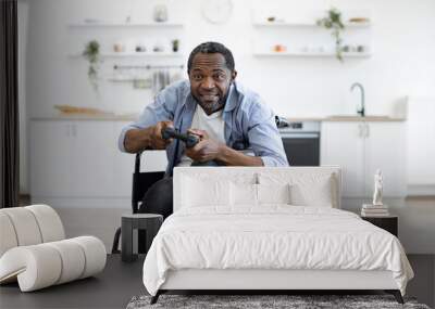 Close up view of african male gamer with mobility impairment with input devices in spacious kitchen in home interior. Joyous competitor honing skills in video games while pursuing enjoyable pastime. Wall mural