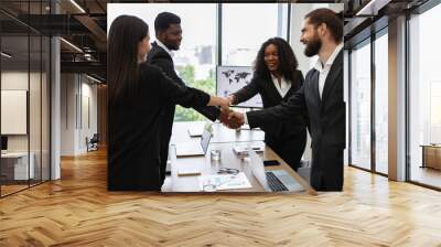 Group of diverse business professionals shaking hands in a modern office setting, showcasing teamwork and successful collaboration. Wall mural