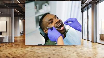 High angle view of male african american patient being examined by dentist in clinic Wall mural