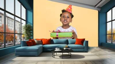 Kid birthday gift. Happy smiling African girl child, wearing red party hat, holds a green present gift box. Holiday, party, birthday concept Wall mural