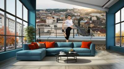 Lady warming-up legs before training on gravel roof Wall mural