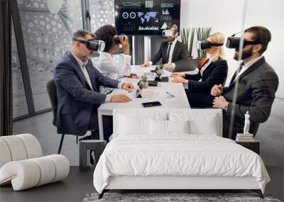 Multiethnic creative business team using virtual reality headsets at the meeting in modern office. Group of developers using virtual reality simulators, sitting around table in office. Wall mural