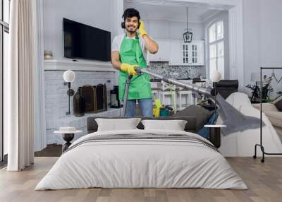 Smiling man cleaning sofa and listening music Wall mural