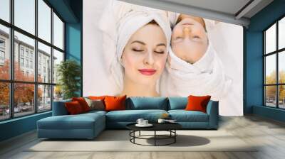 Top view of beautiful young mother and her two year old daughter lying on the bed at home, relaxing after nice spa bath procedures with eyes closed. Family spa and beauty care Wall mural