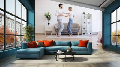 Young caucasian lady dancing with male partner while robotic vacuum running floor smoothly. Homeowners using electrical appliance for household chores while freeing up time for mother-daughter party. Wall mural