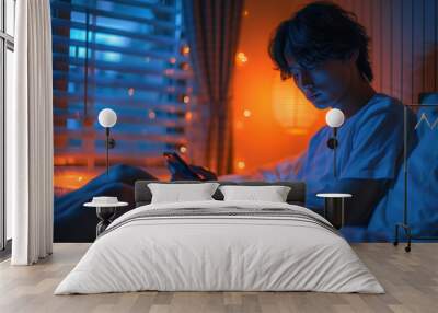 Young man using smartphone in cozy evening bedroom light Wall mural