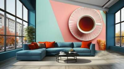 A top view of a cup of tea with a saucer and two puff pastries on a dual-tone background, creating a fresh and modern breakfast concept with copy space Wall mural