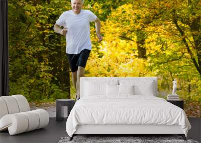 Active mature man running in autumn park Wall mural